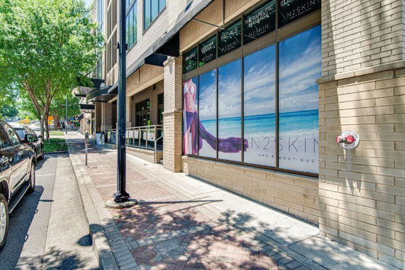 Front view of a multi-story commercial building with large windows and a sidewalk.