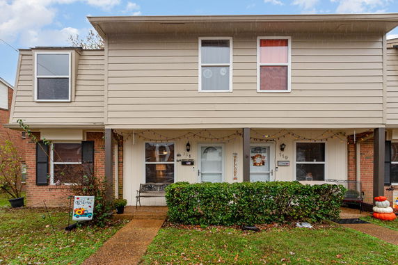 Front view of a two-story townhouse with decorative elements and a small porch.