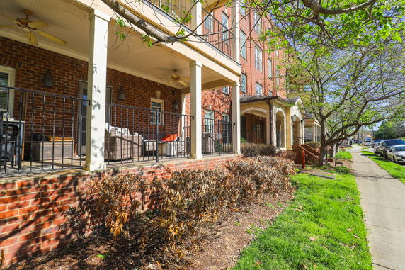 Front view of a multi-story building with a porch and railing.