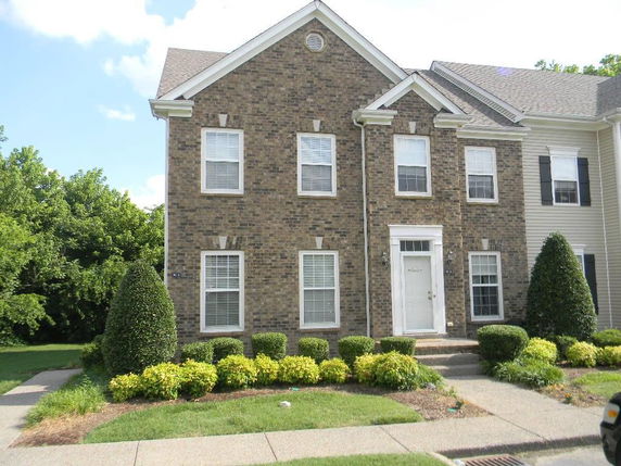 Front view of a two-story brick house with white framed windows and a white door.