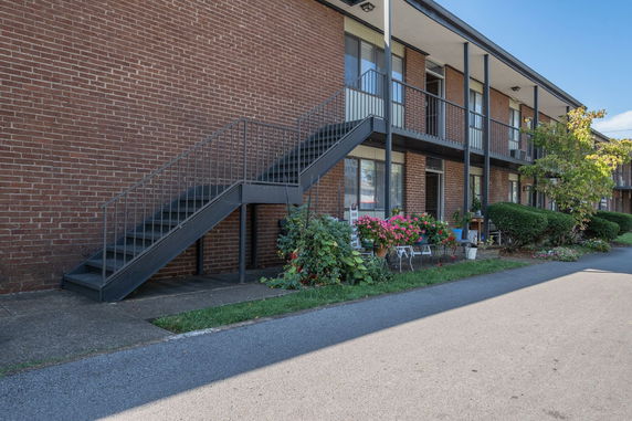 Front view of a brick building with an external staircase and balcony.
