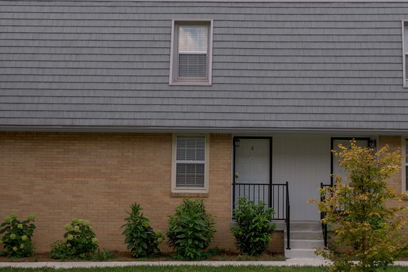 Front view of a house with brick facade and shingled roof.