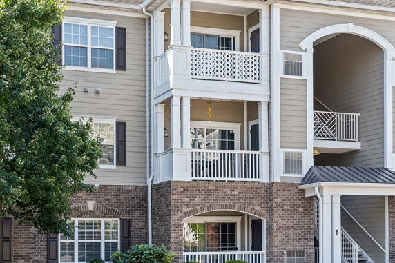 Front view of a multi-story apartment building with balconies and brick facade.