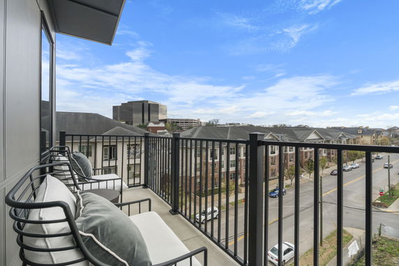 View from a balcony overlooking a street and buildings in a residential area.