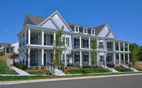 Front view of a multi-story house with multiple gables and a wraparound porch.