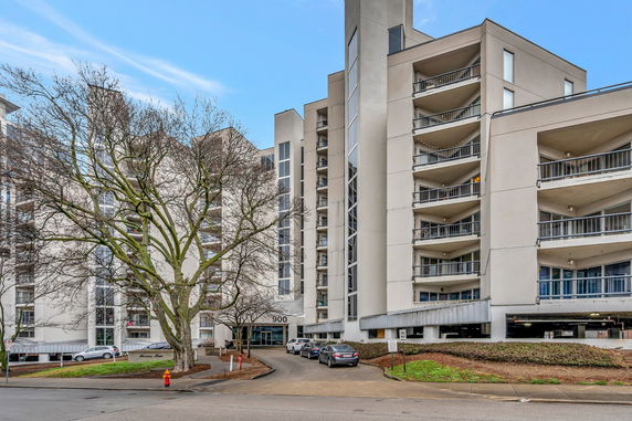 Front view of a multi-story apartment building with balconies and parking area.