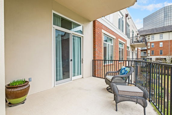 View from a balcony with outdoor furniture, overlooking a row of buildings.