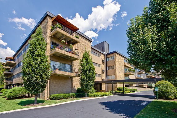 Front view of a multi-story brick building with balconies and covered parking area.