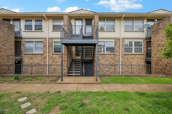 Front view of a two-story brick apartment building with metal staircases.