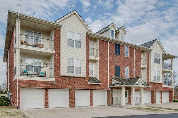 Front view of a multi-story building with brick and siding exterior and multiple garages.