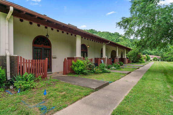 Front view of a long, single-story building with a covered walkway and decorative fencing.