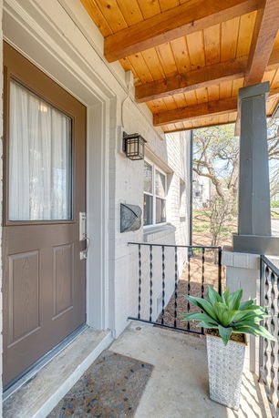 Front entrance view of a house with a wooden porch and a decorative plant.