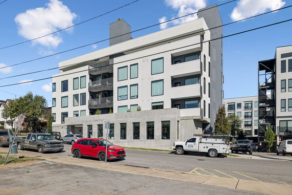 Front view of a modern multi-story apartment building with balconies and large windows.