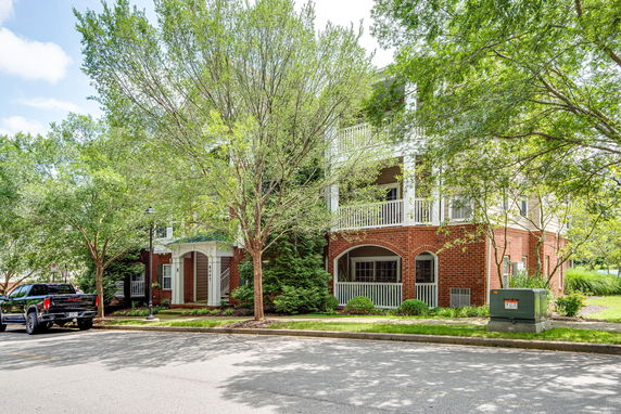 Front view of a multi-story brick building with balconies and white railings.