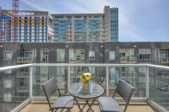 Balcony view overlooking modern apartment buildings with outdoor seating area.