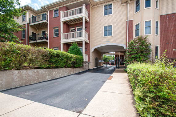 Front view of a multi-story building with balconies and a gated entrance.