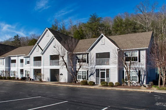 Front view of a multi-story residential building with a sloped roof and white siding.