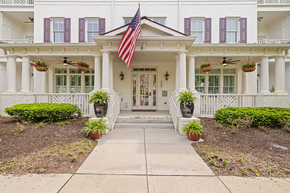 Front view of a large, white, two-story building with columns and an American flag.