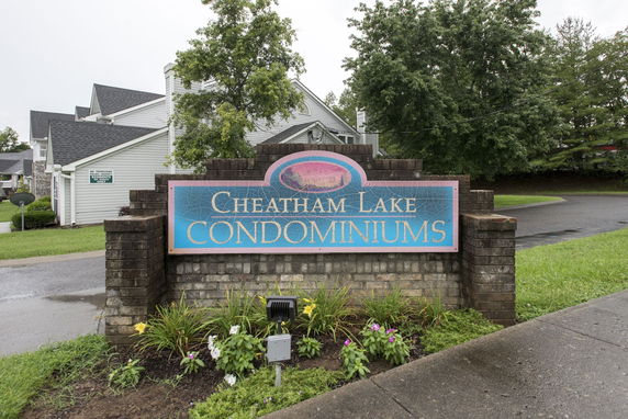 Front view of a condominium complex entrance sign with surrounding buildings.