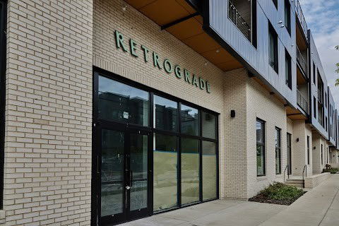 Front view of a modern multi-story building with large windows and brickwork.