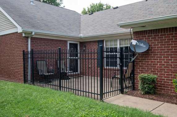 Front view of a house with a brick exterior and fenced patio.