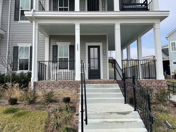 Front view of a two-story house with a small porch and stairs leading up to the entrance.