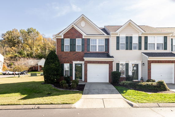 Front view of a two-story townhouse with a garage and brick facade.