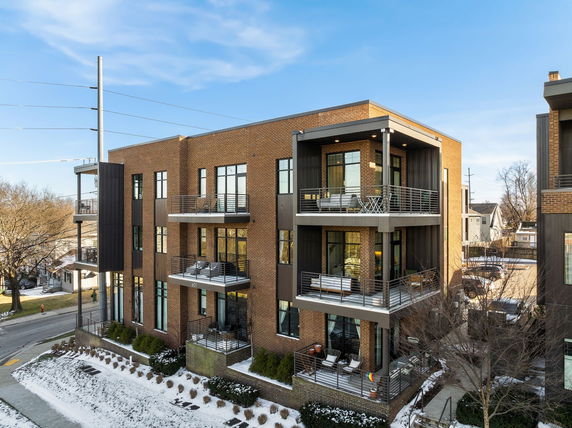 Front view of a multi-story brick apartment building with balconies.