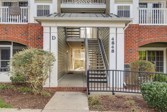Front view of a multi-story residential building entrance with stairs.