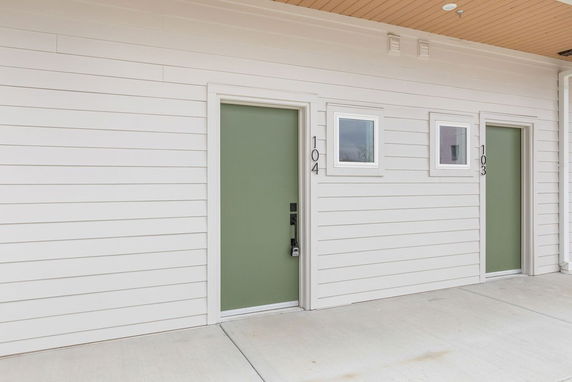 Front view of a building with two green doors numbered 103 and 104.