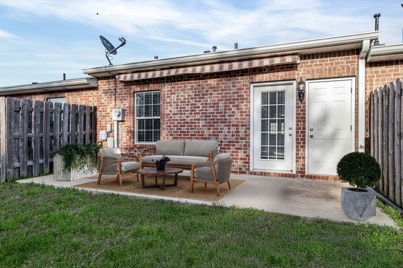 Brick exterior of a house with a patio area and outdoor seating.