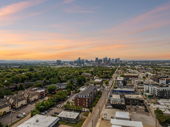 Panoramic view of a cityscape with high-rise buildings, residential areas, and greenery at sunset.