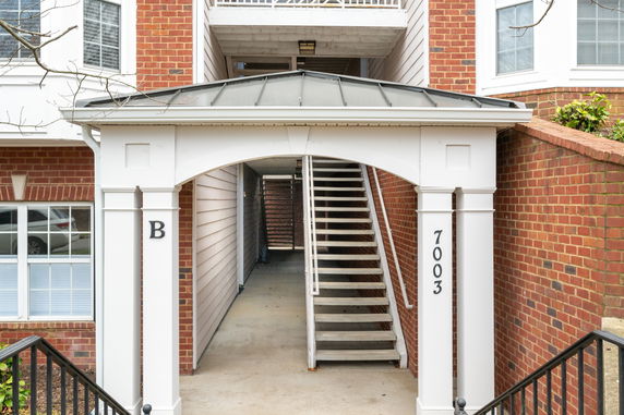 Front view of a two-story brick building with an entrance labeled 'B' and stairs leading to upper floors.