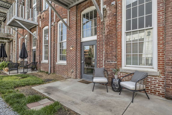 Front view of a brick building with large windows and a patio area.
