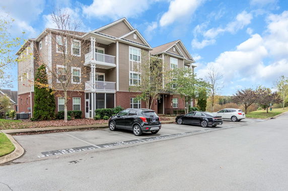 Front view of a multi-story apartment building with balconies and parking area.