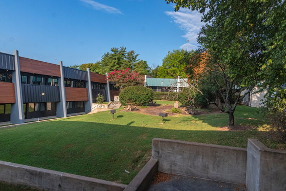 Front view of a building with modern design and wooden accents, surrounded by greenery.