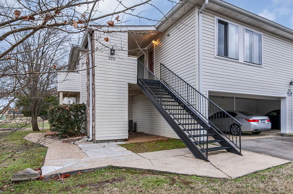 Front view of a two-story house with an external staircase and garage.