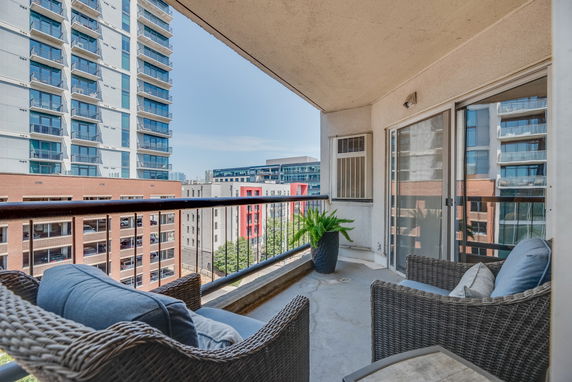 Balcony with outdoor chairs overlooking city buildings.