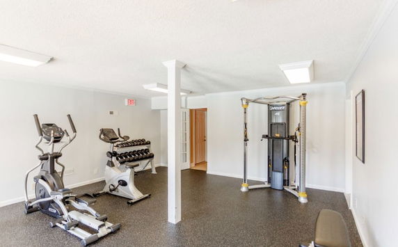 Indoor gym area with exercise equipment including an elliptical machine, weight rack, and multi-gym equipment.