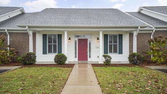 Front view of a single-story house with a red door and brick siding.