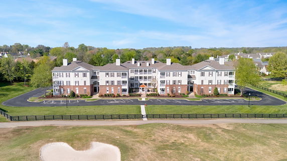 Front view of a multi-story residential building with parking area.