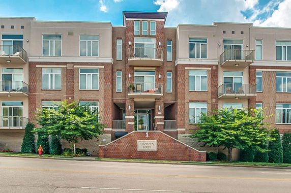 Front view of a multi-story brick building with balconies and large windows.
