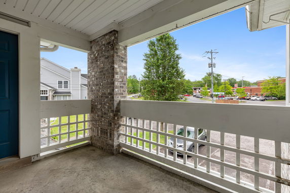 View from a porch overlooking a parking area and surrounding buildings.