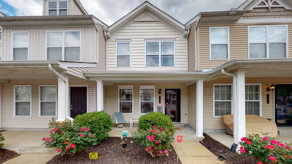 Front view of a two-story townhouse with a porch and columns.