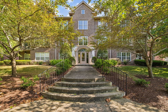 Front view of a multi-story brick building with stairs leading to the entrance.