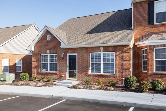 Front view of a single-story brick house with a gable roof and white windows.