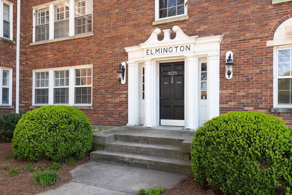 Front view of a brick building entrance with decorative columns and double doors.
