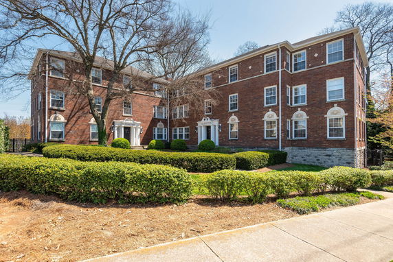 Front view of a brick multi-story building with symmetrical windows and entrance.