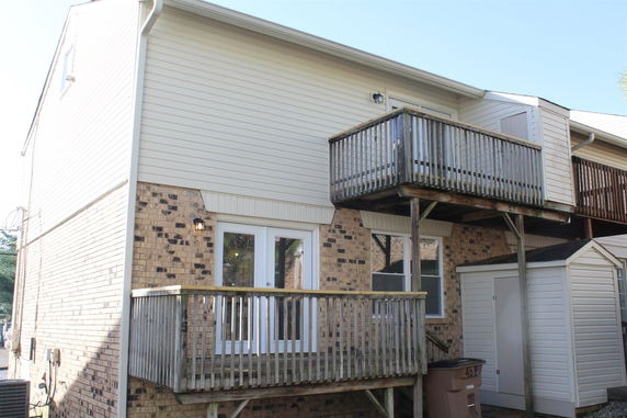 Rear view of a two-story house with a small upper and lower deck.