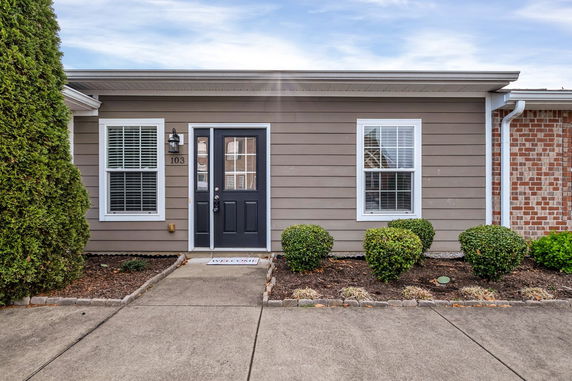 Front view of a single-story house with black door and two windows.
